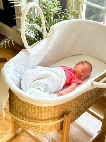 Baby girl sleeping in moses basket