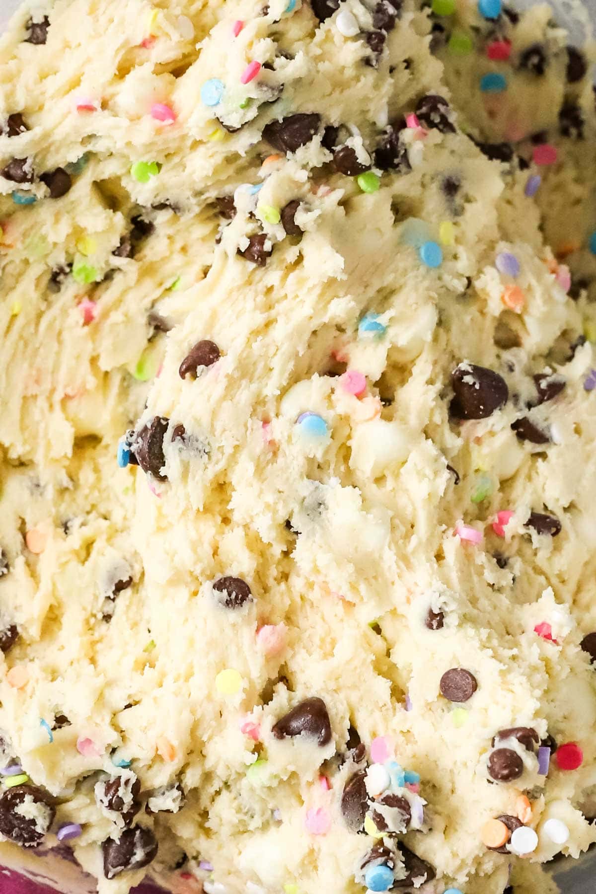 Close-up view of cookie dough flecked with chocolate chips and sprinkles.