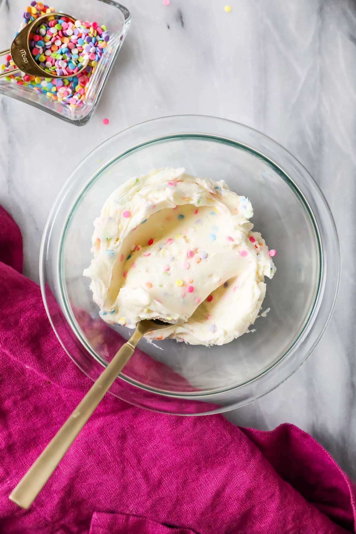 Overhead view of a small bowl of sprinkle flecked buttercream.