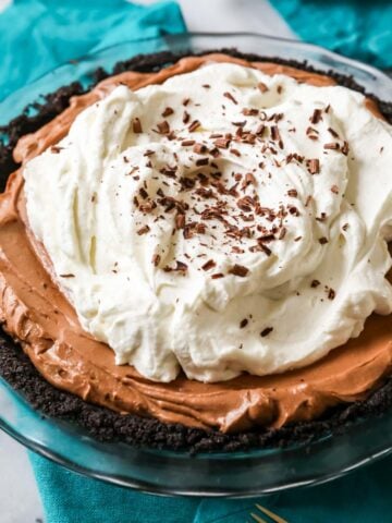 Mississippi mud pie topped with a thick layer of whipped cream and chocolate shavings.