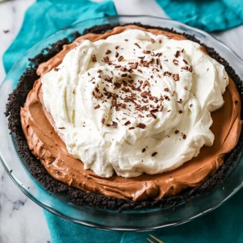 Mississippi mud pie topped with a thick layer of whipped cream and chocolate shavings.