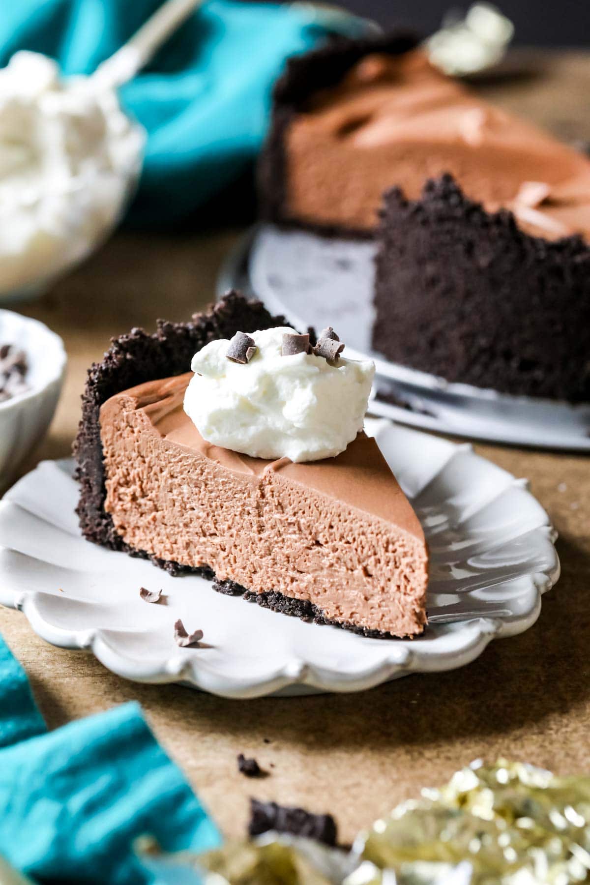 Slice of no-bake chocolate cheesecake topped with whipped cream on a white plate.