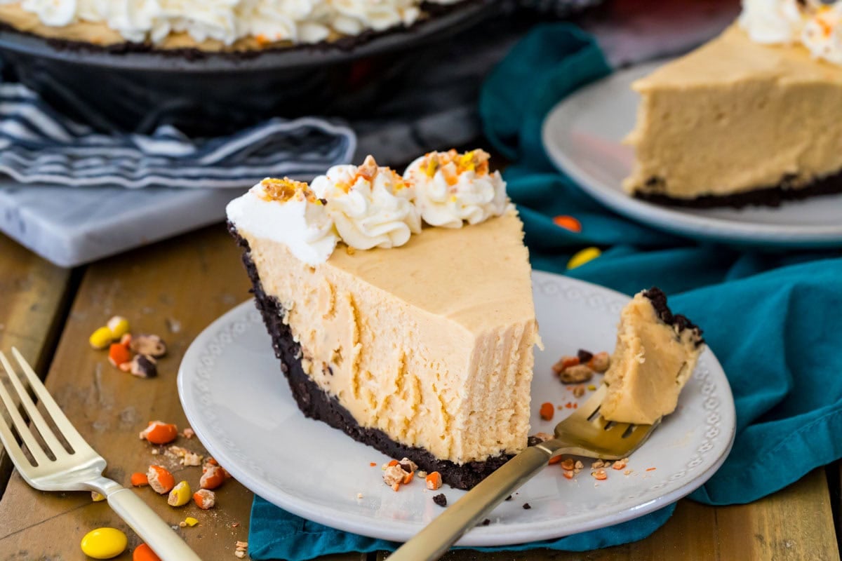 Slice of no-bake pie made with a peanut butter filling and an Oreo crust with one bite on a fork beside the pie.