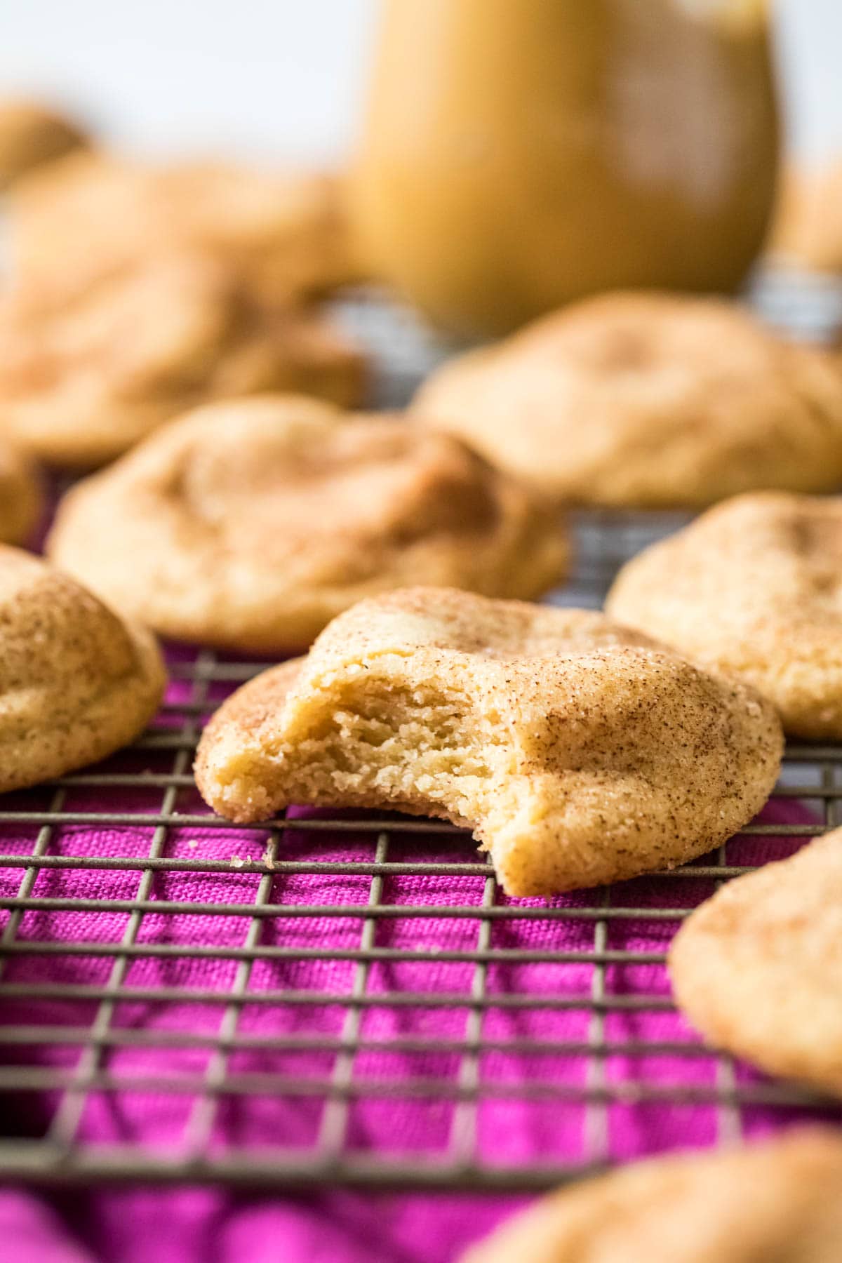 Bite missing from a peanut butter snickerdoodle cookie on a cooling rack.