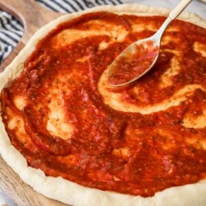 Pizza sauce being spread onto a crust.