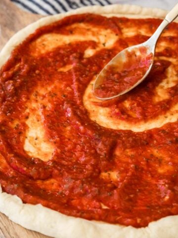 Pizza sauce being spread onto a crust.