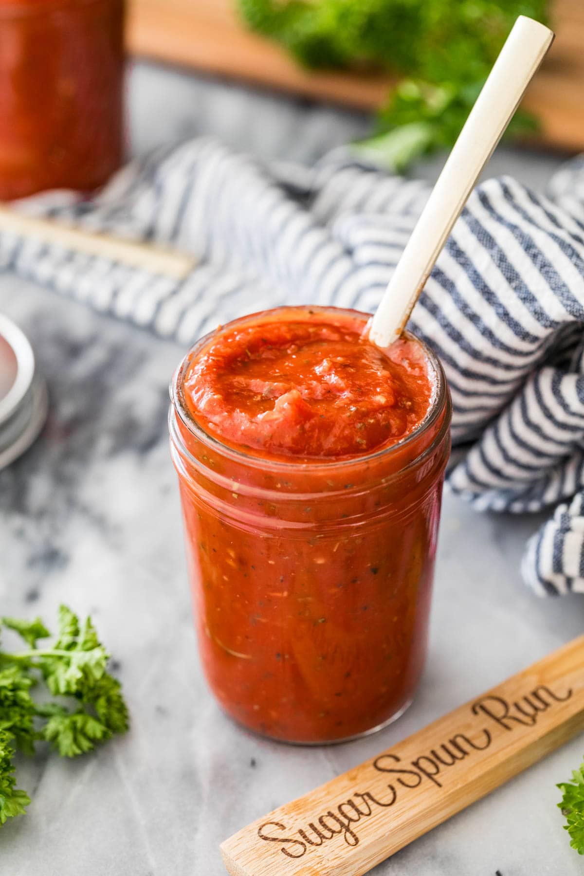 Glass jar of homemade pizza sauce with a spoon in it. 