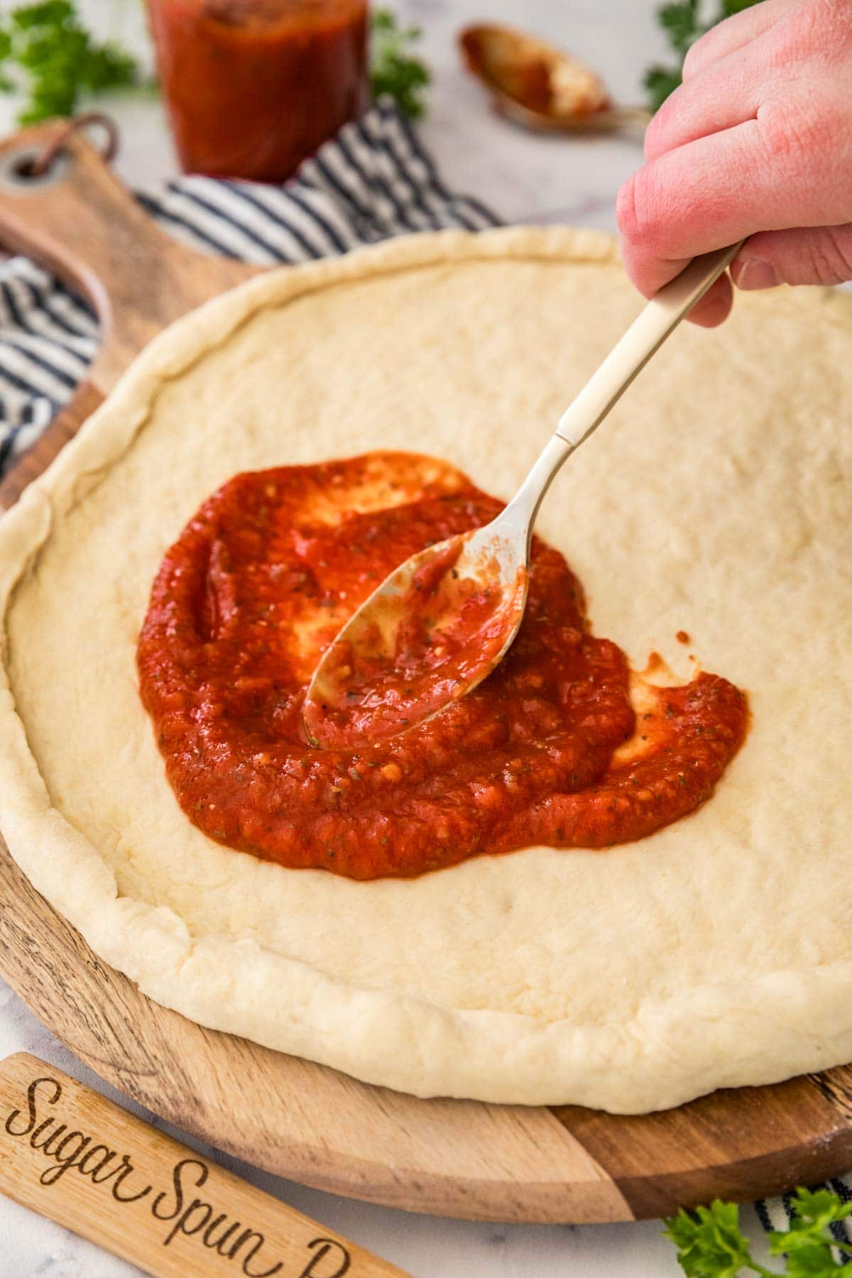 Red sauce being spread onto a pizza crust.