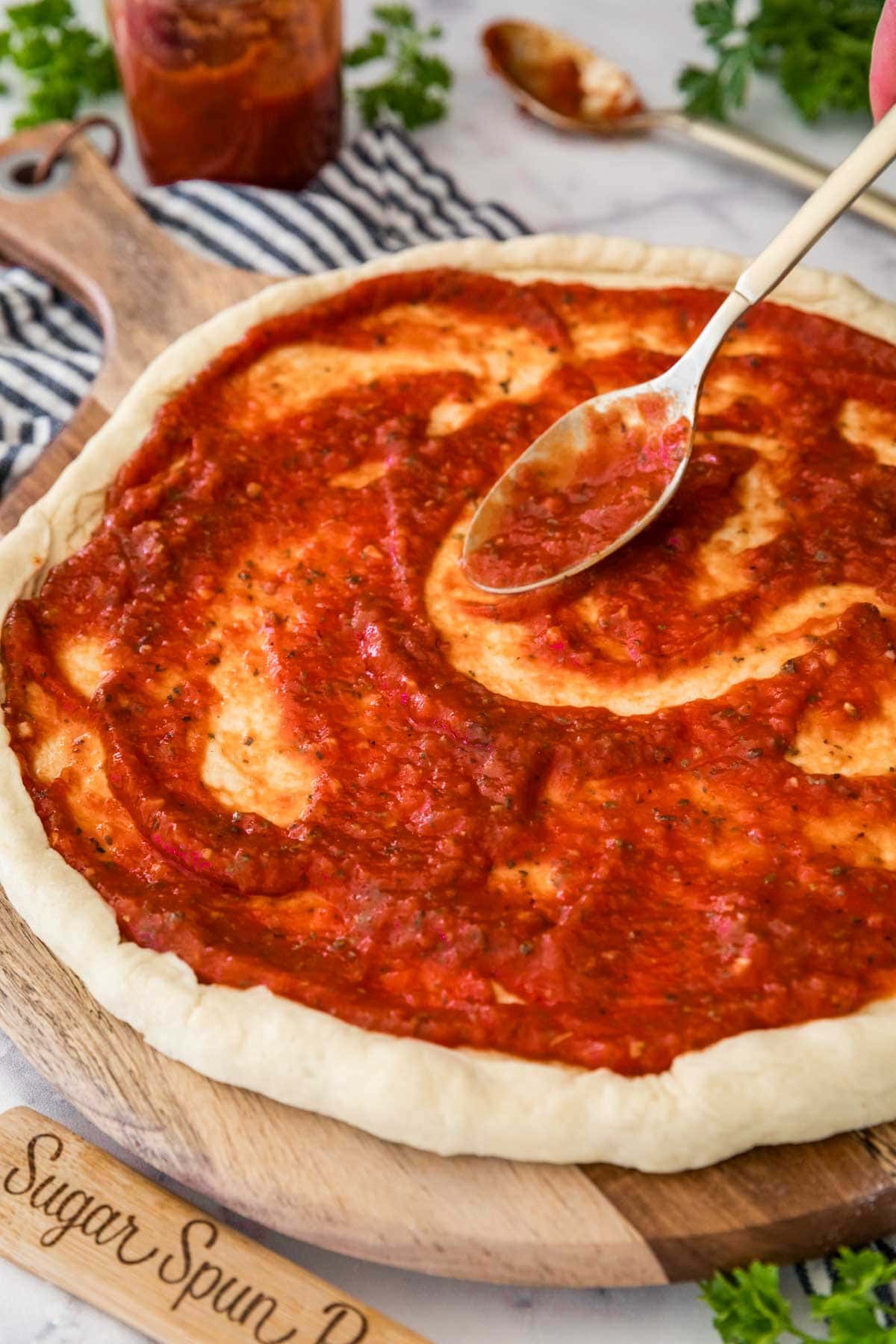 Pizza sauce being spread onto a crust.