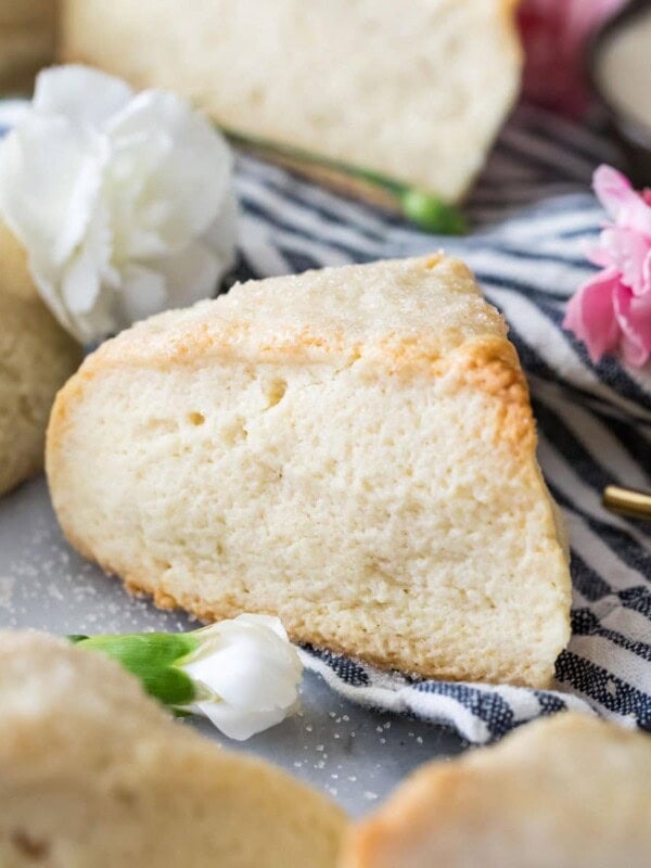 Close-up view of a tall, wedge-shaped scone surrounded by other scones on a striped towel.