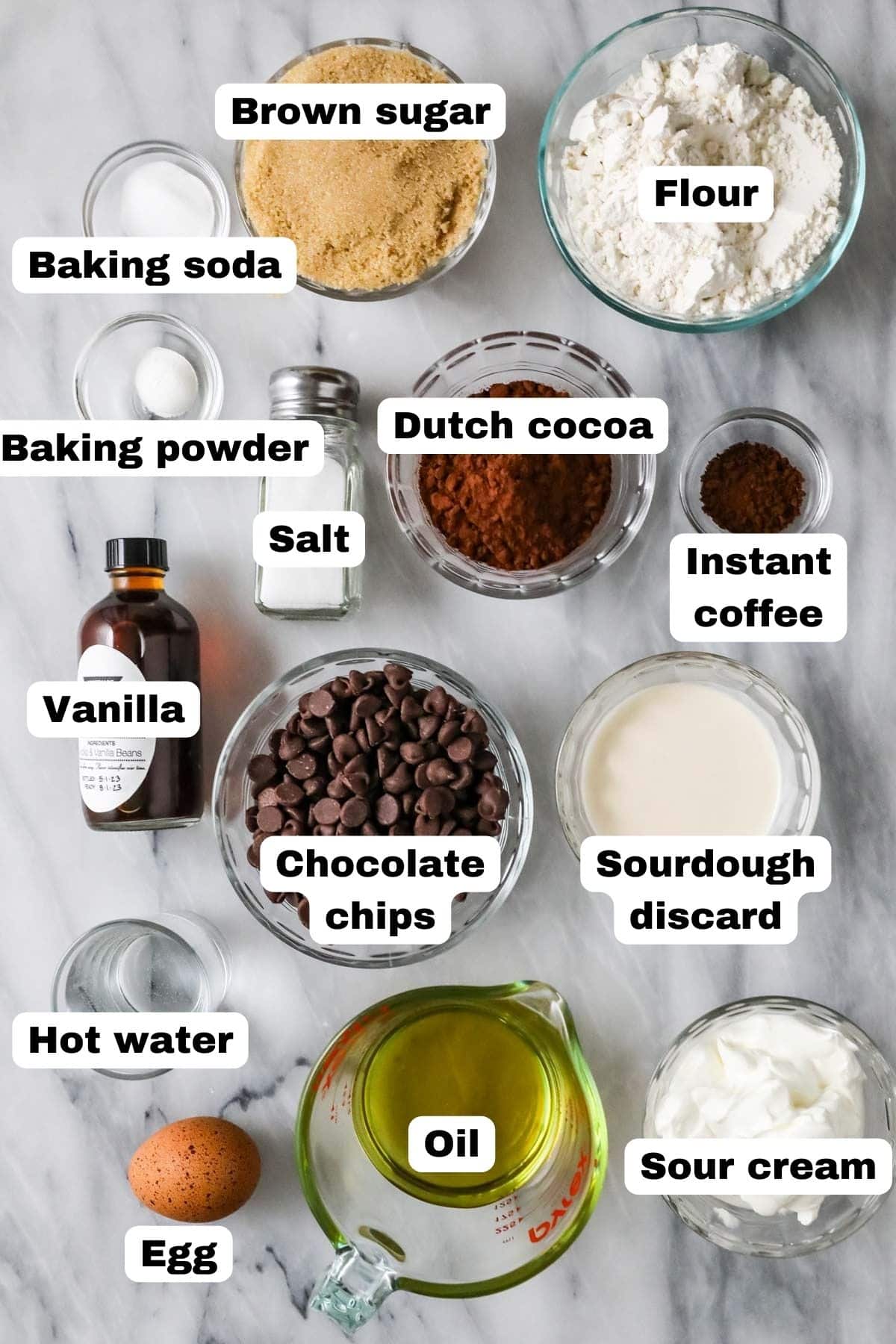 Overhead view of labeled ingredients including cocoa powder, sourdough discard, oil, and more.