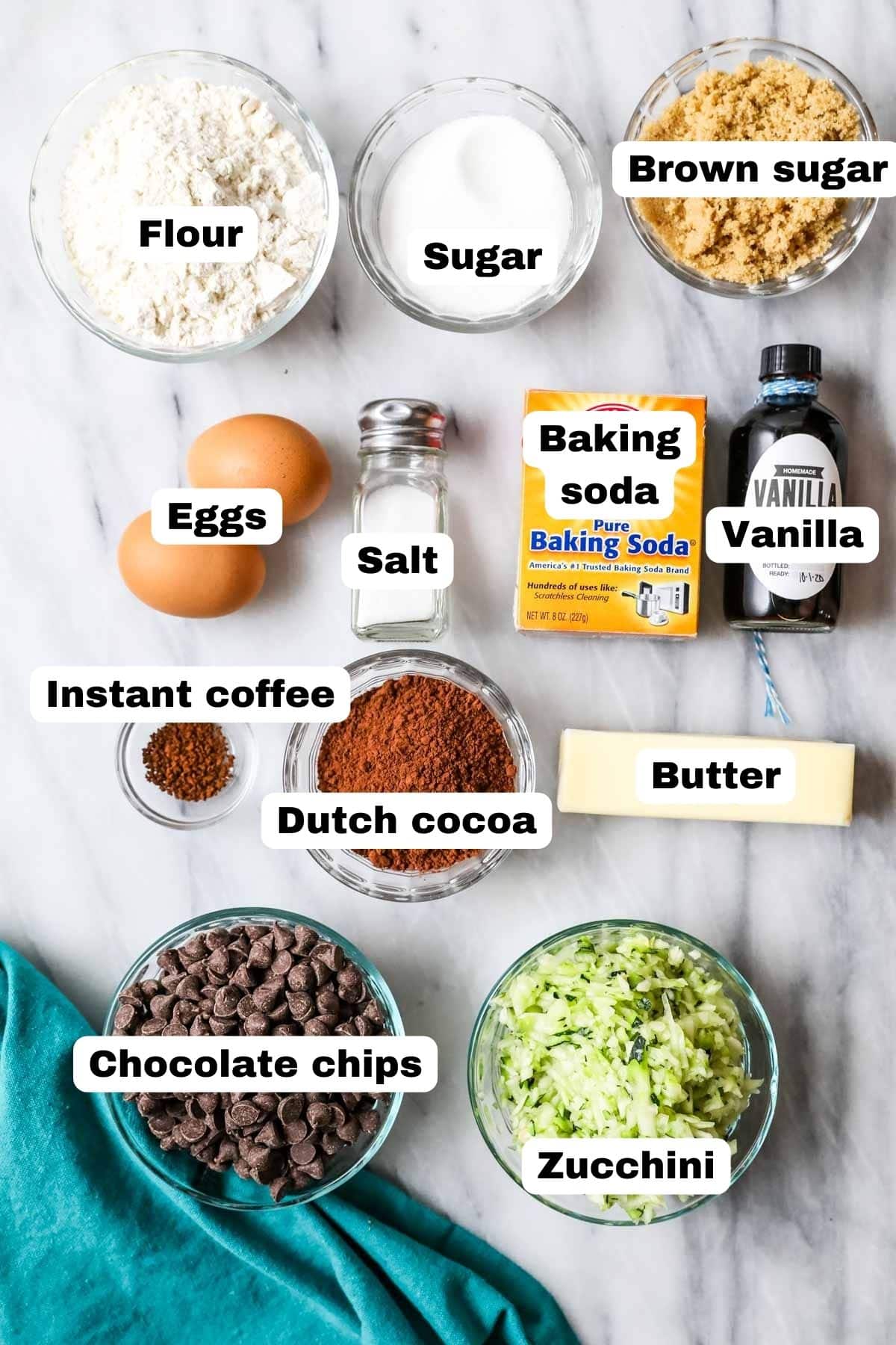 Overhead view of labeled ingredients including shredded zucchini, cocoa powder, brown sugar, and more.