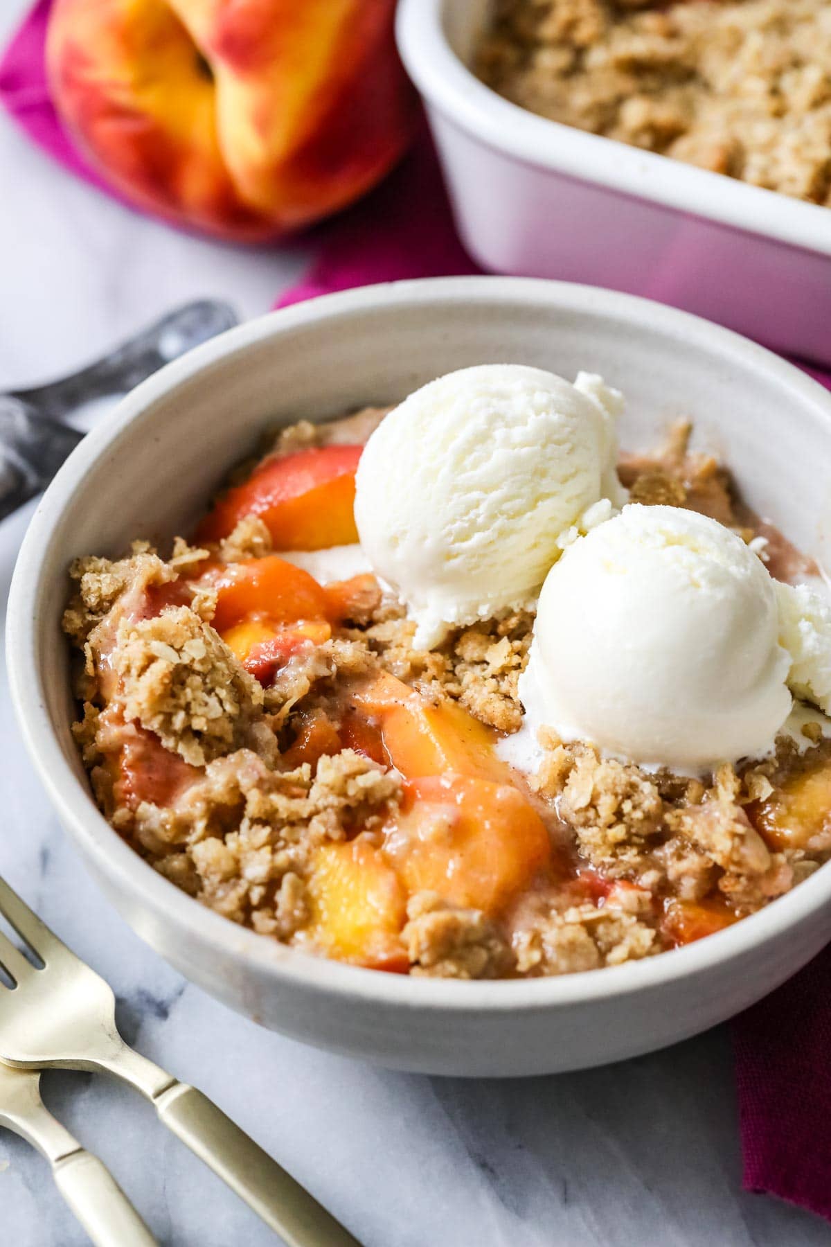 A close-up of a peach dessert topped with oatmeal and vanilla ice cream.