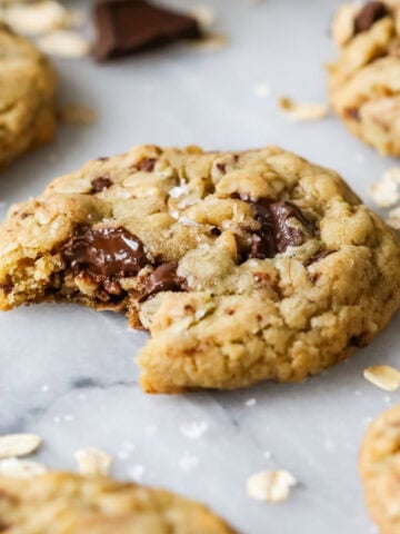 Close-up view of a brown butter oatmeal chocolate chip cookie with a bite missing.