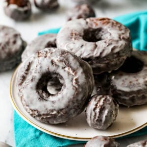 Old fashioned chocolate donuts with a vanilla glaze on a plate.