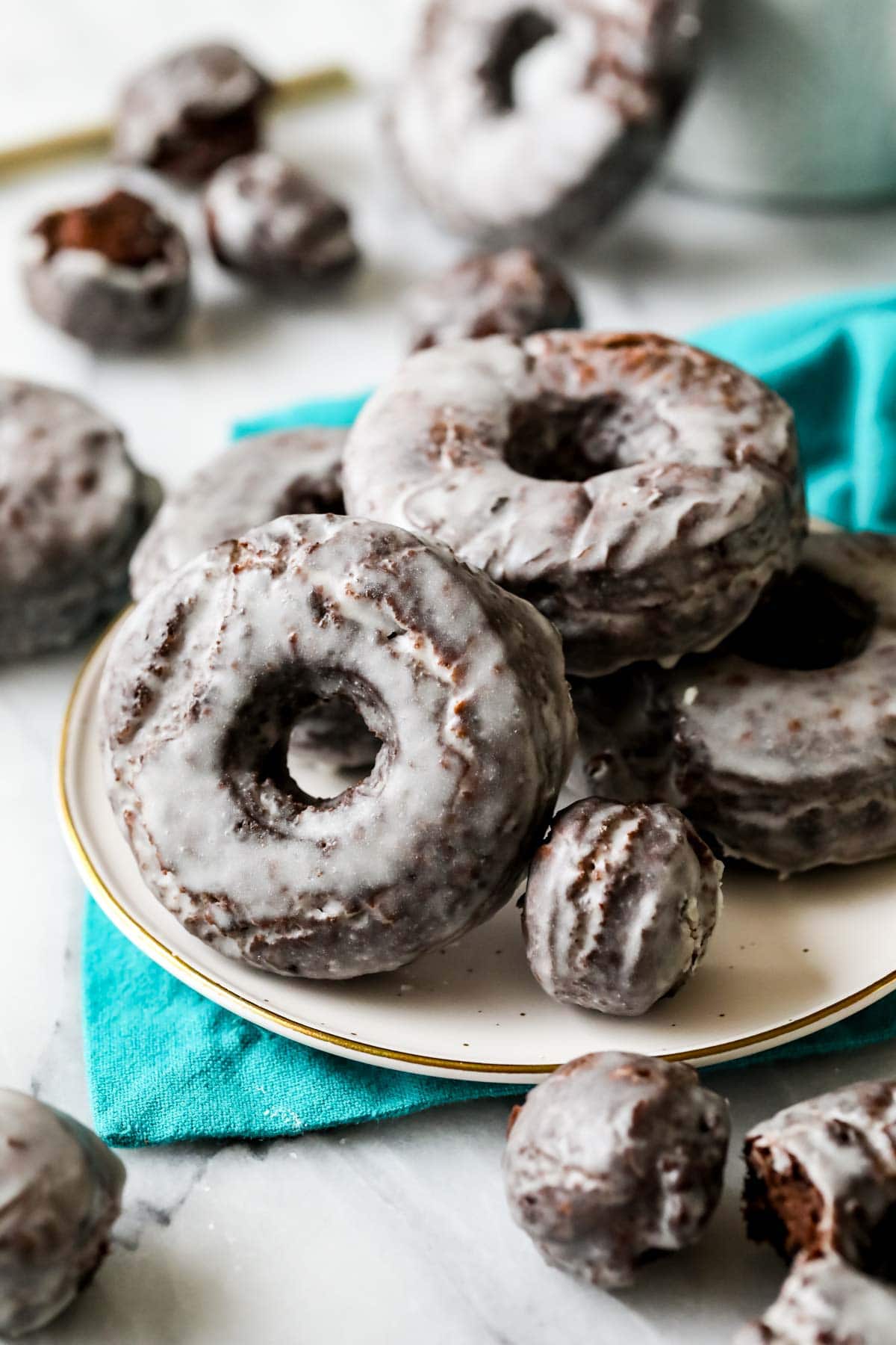 Old fashioned chocolate donuts with a vanilla glaze on a plate.