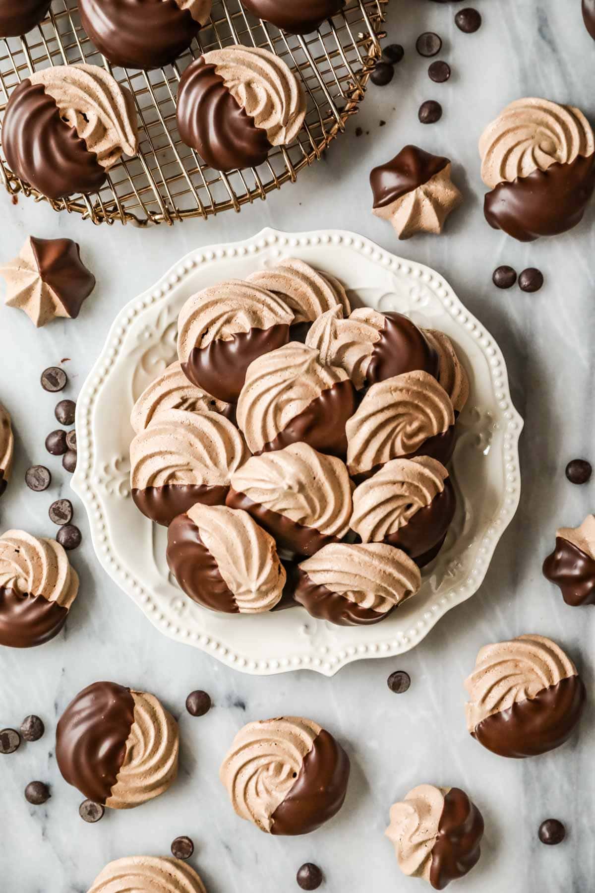 Overhead view of a plate of chocolate meringues that have been half dipped in chocolate.