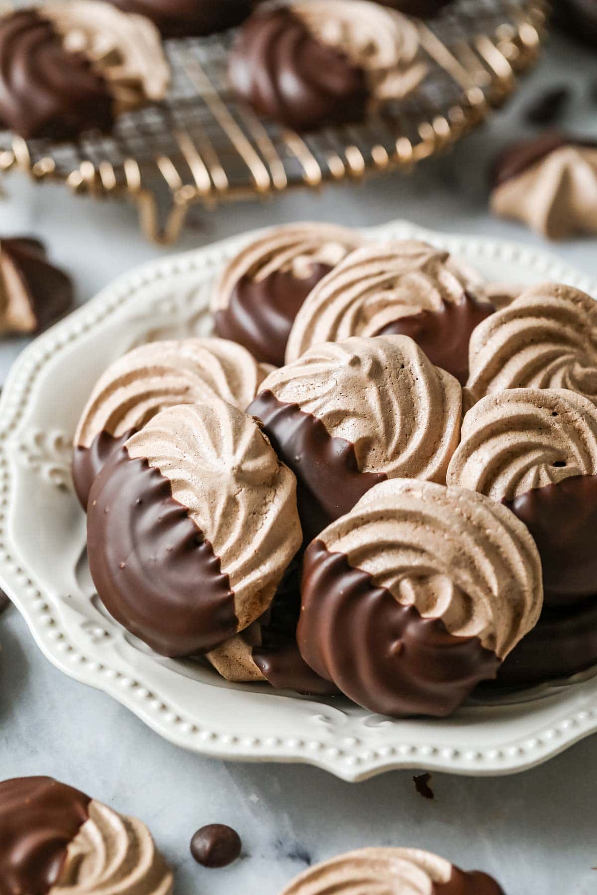 Plate of chocolate meringues that have been half dipped in chocolate.