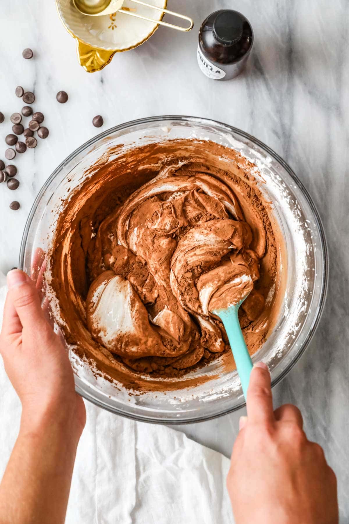 Overhead view of cocoa being folded into meringue with a spatula.