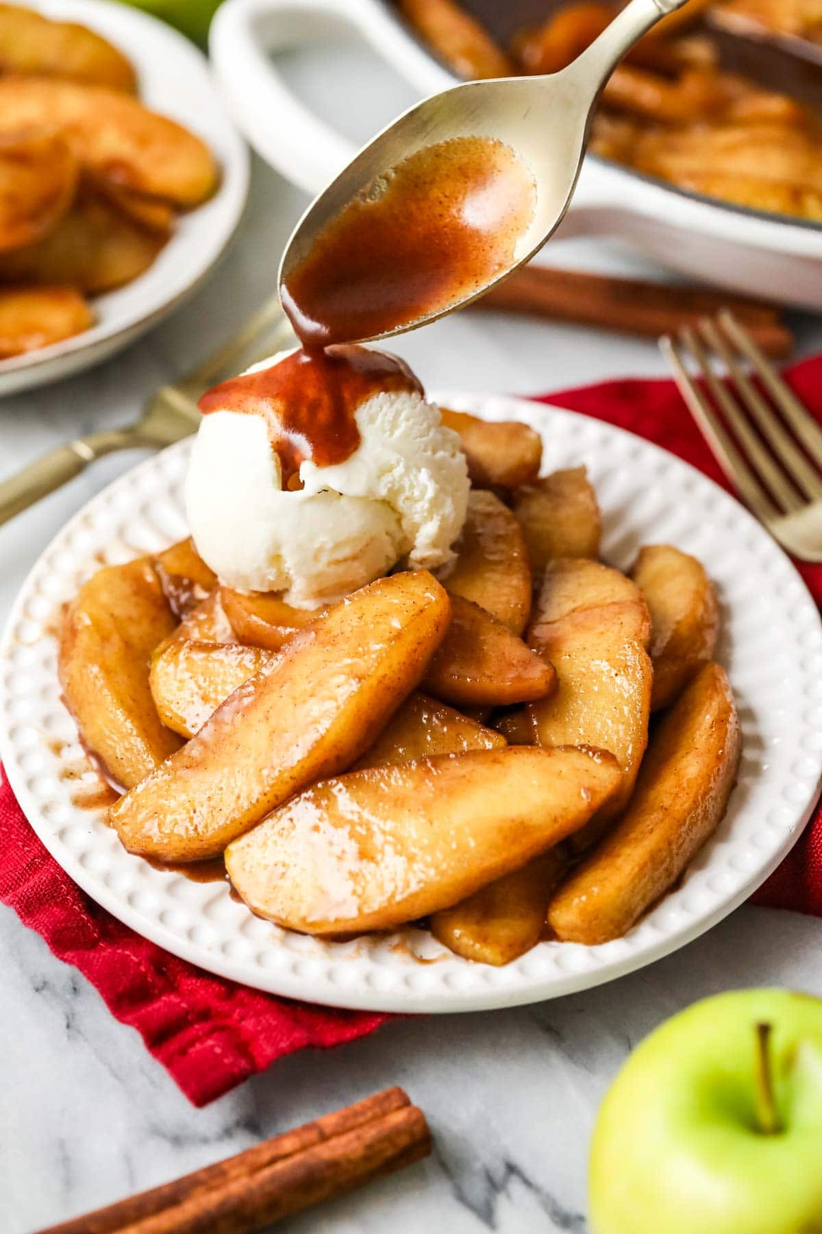 A plate of fried apples is topped with a scoop of vanilla ice cream.