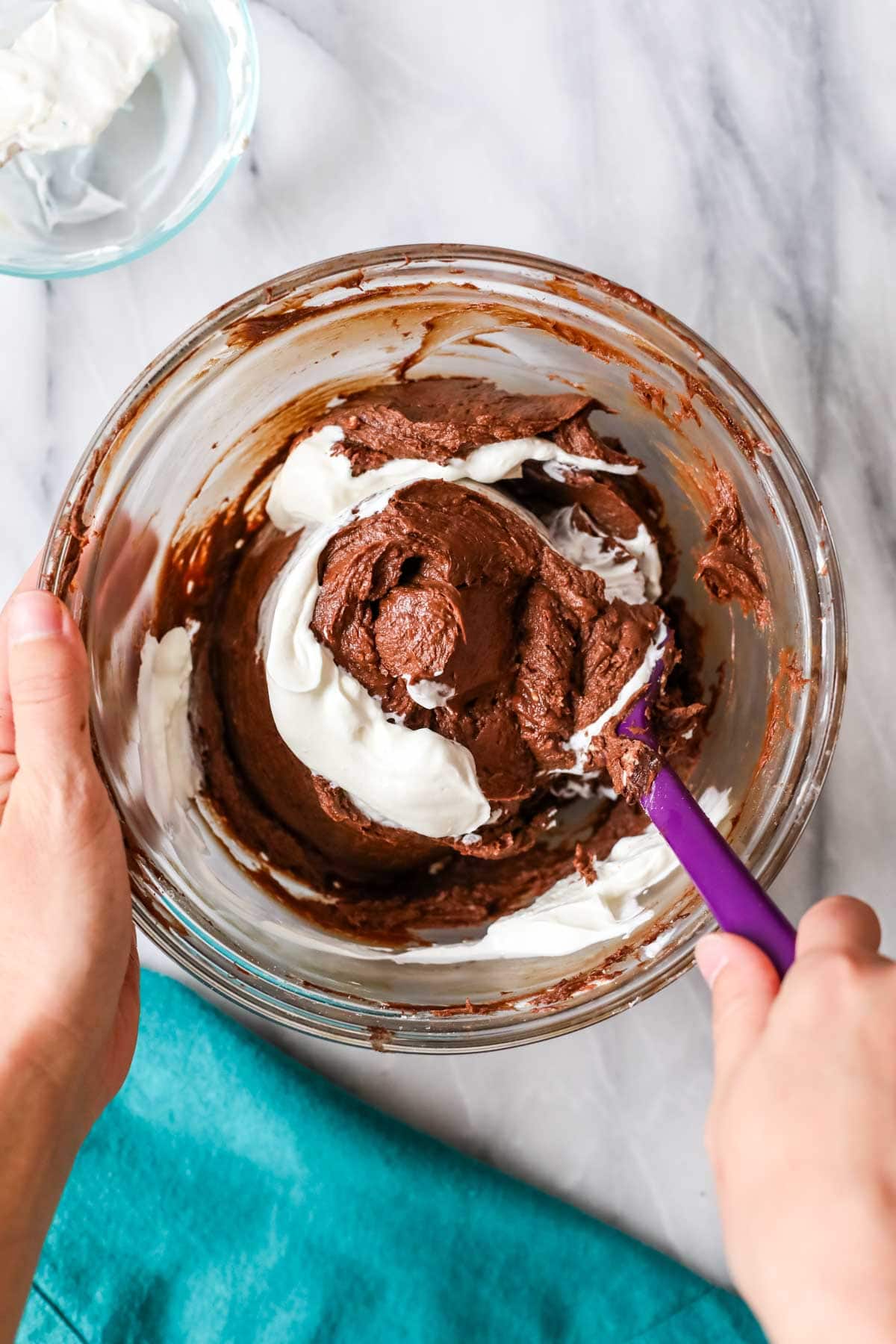 Melted chocolate being folded into a cream cheese mixture.