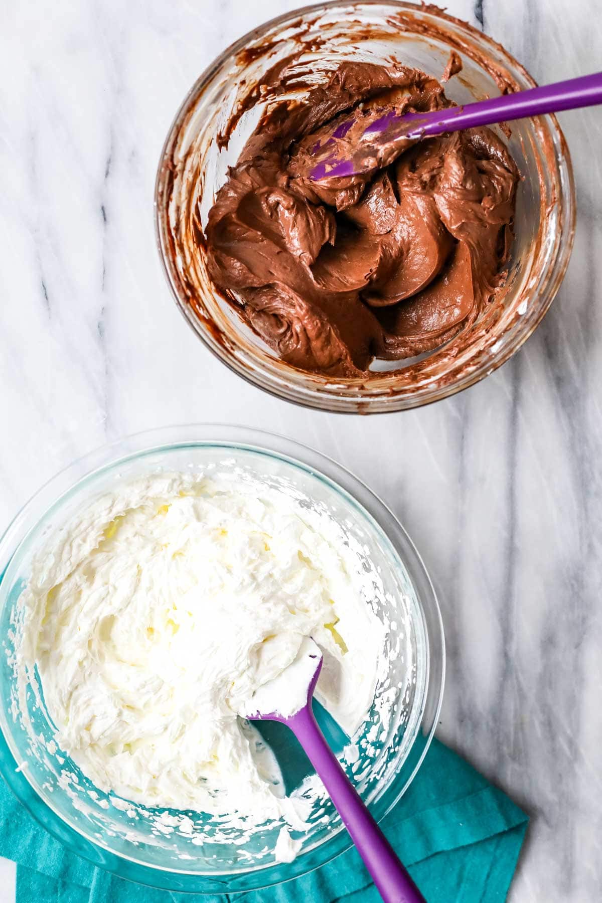 Overhead view of two bowls beside each other, one with whipped cream and the other with a chocolate cream cheese mixture.