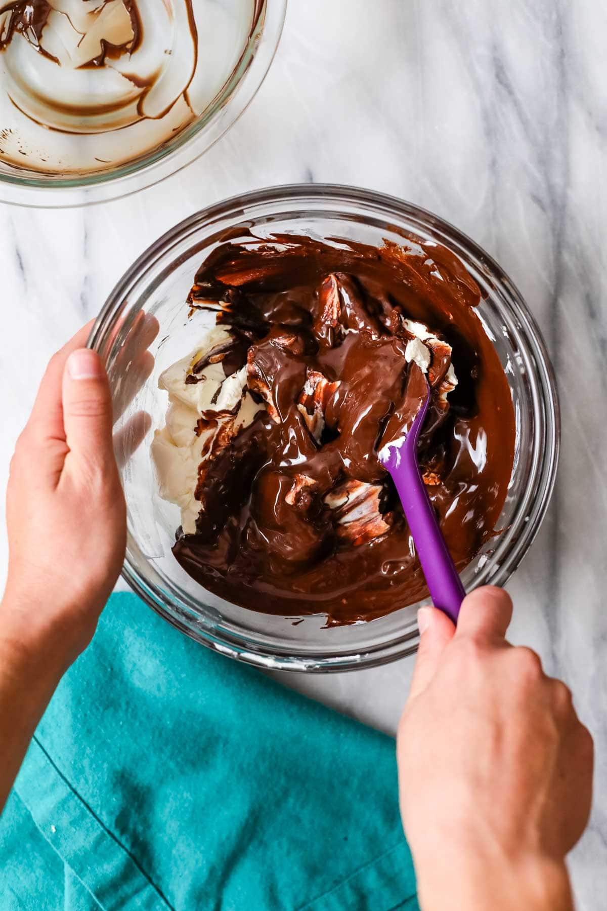 Overhead view of melted chocolate being combined with cream cheese. 