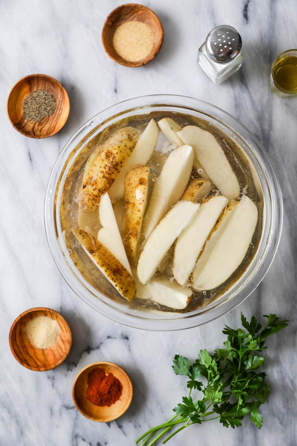 Overhead view of a bowl of potatoes soaking in water.