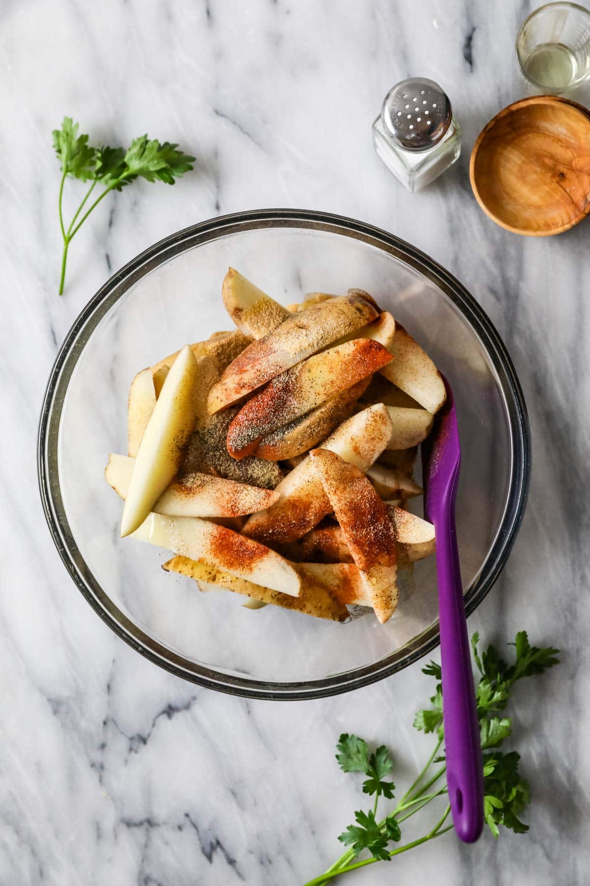 Overhead view of potato spears topped with spices.