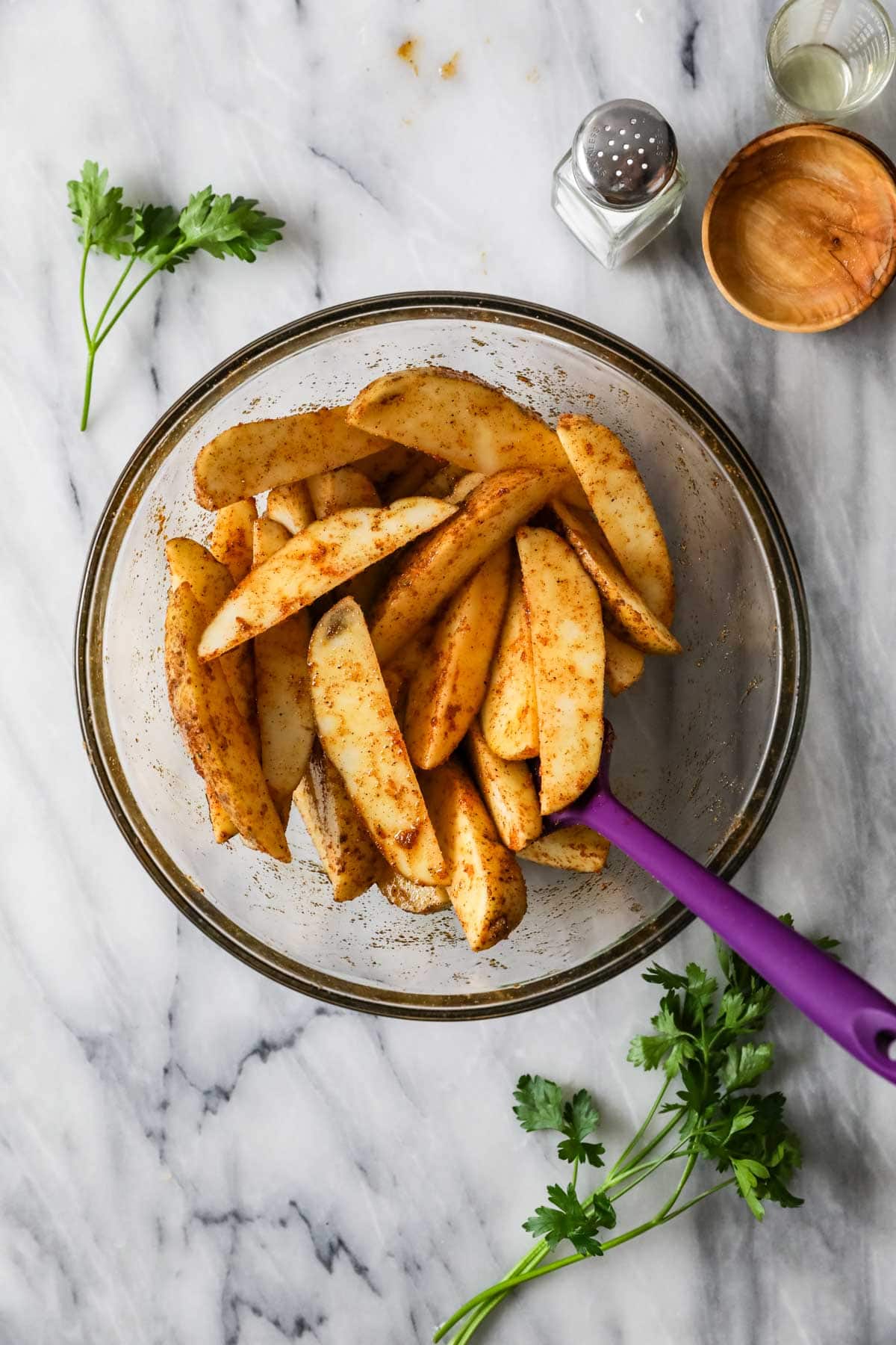 Overhead view of a bowl of seasoned potato spears.