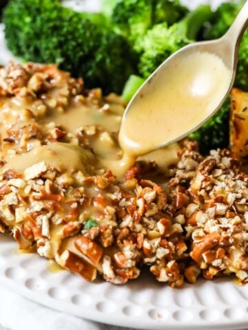 Honey mustard sauce being drizzled over pretzel crusted chicken.