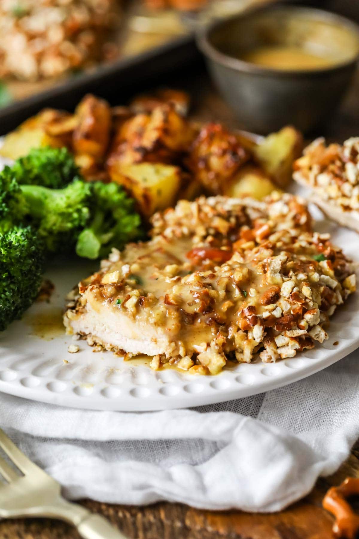 Chicken cutlet encrusted with pretzel pieces with one bite missing.