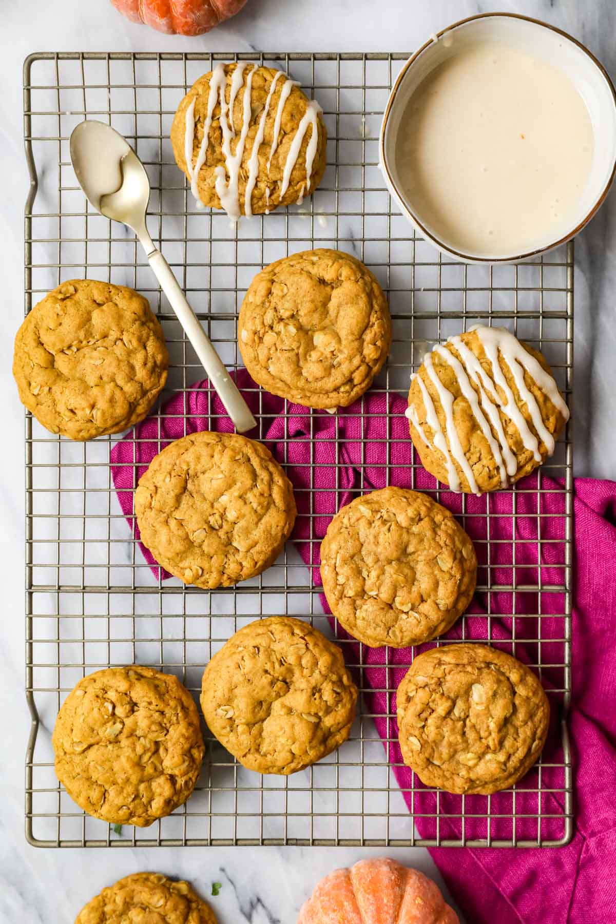 Overhead view of pumpkin oat cookies being drizzled with a brown sugar glaze.