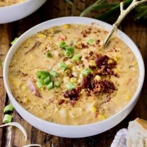 Bowl of summer corn chowder topped with scallions and bacon.