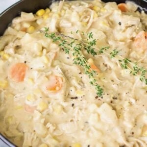 Close-up view of a bowl of turkey chowder topped with fresh thyme and black pepper.