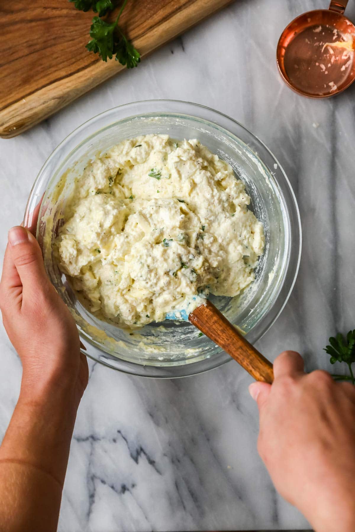 Overhead view of a cheese and herb pastsa filling being stirred together.