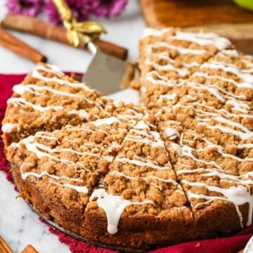 Apple crumb cake cut into slices and drizzled with vanilla glaze.