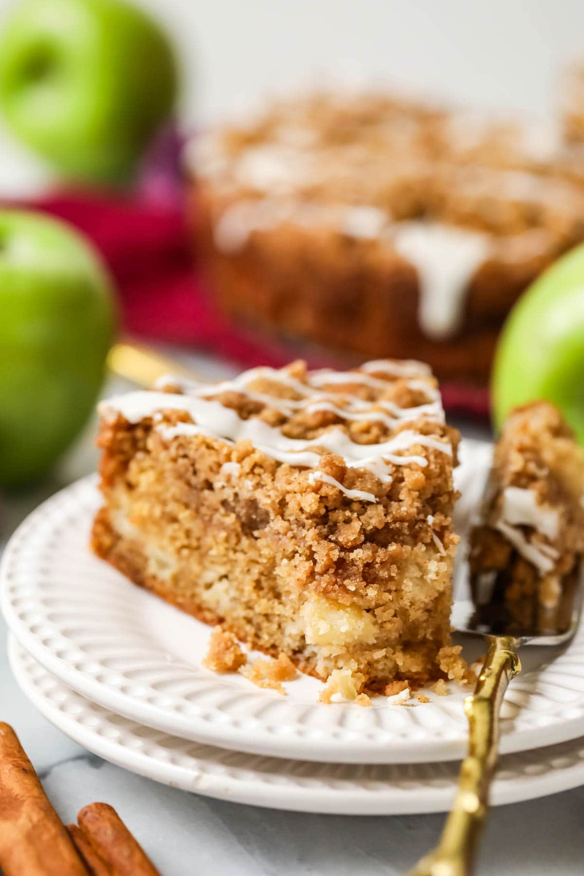 Slice of apple streusel cake on a plate with a forkful missing