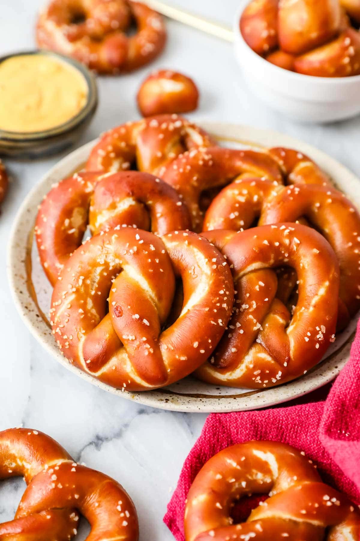 Pile of deep golden brown sourdough soft pretzels on a plate.