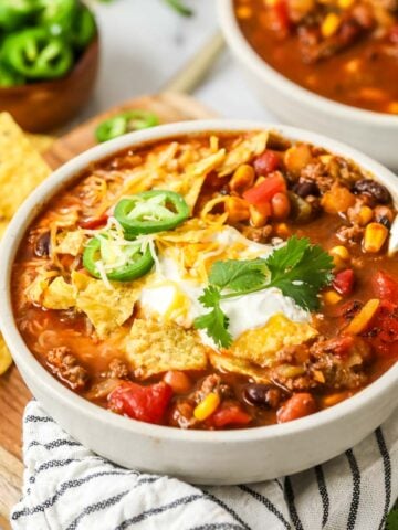 Bowl of taco soup topped with corn chips, jalapeno, sour cream, and more.