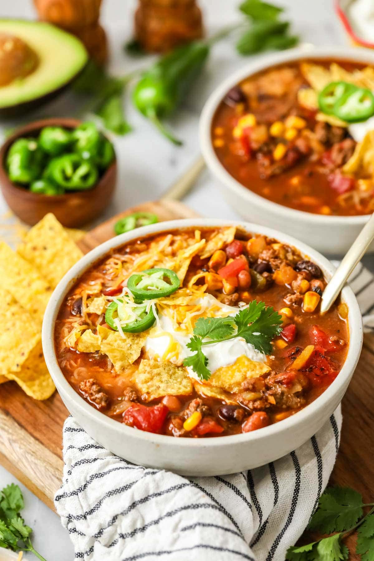 Bowl of taco soup topped with corn chips, jalapeno, sour cream, and more.