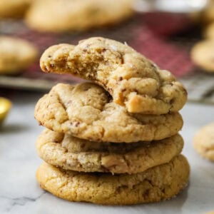 Stack of brown butter toffee cookies with the top cookie missing a bite.