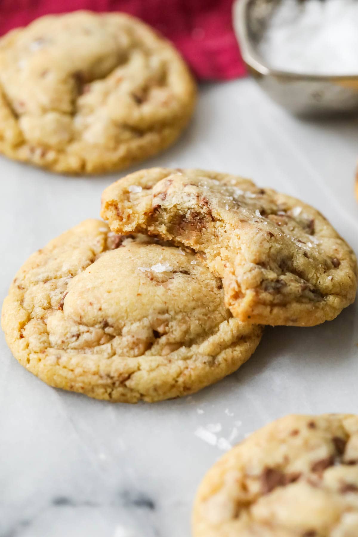 Two brown butter toffee cookies stacked on top of each other with the top cookie missing a bite.