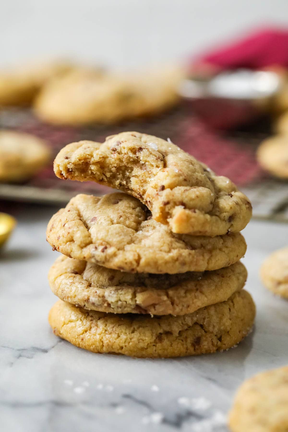 Stack of brown butter toffee cookies with the top cookie missing a bite.