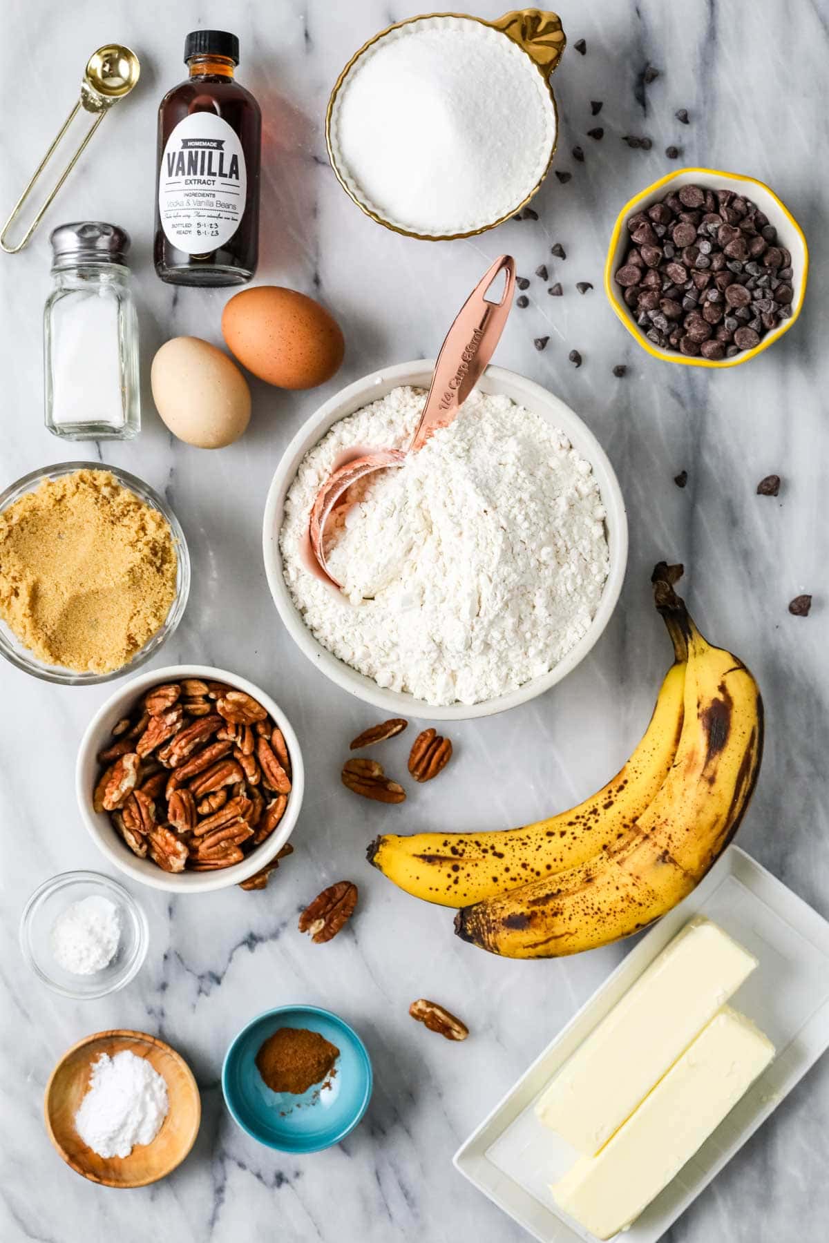 Overhead view of ingredients including bananas, chocolate chips, pecans, and more.