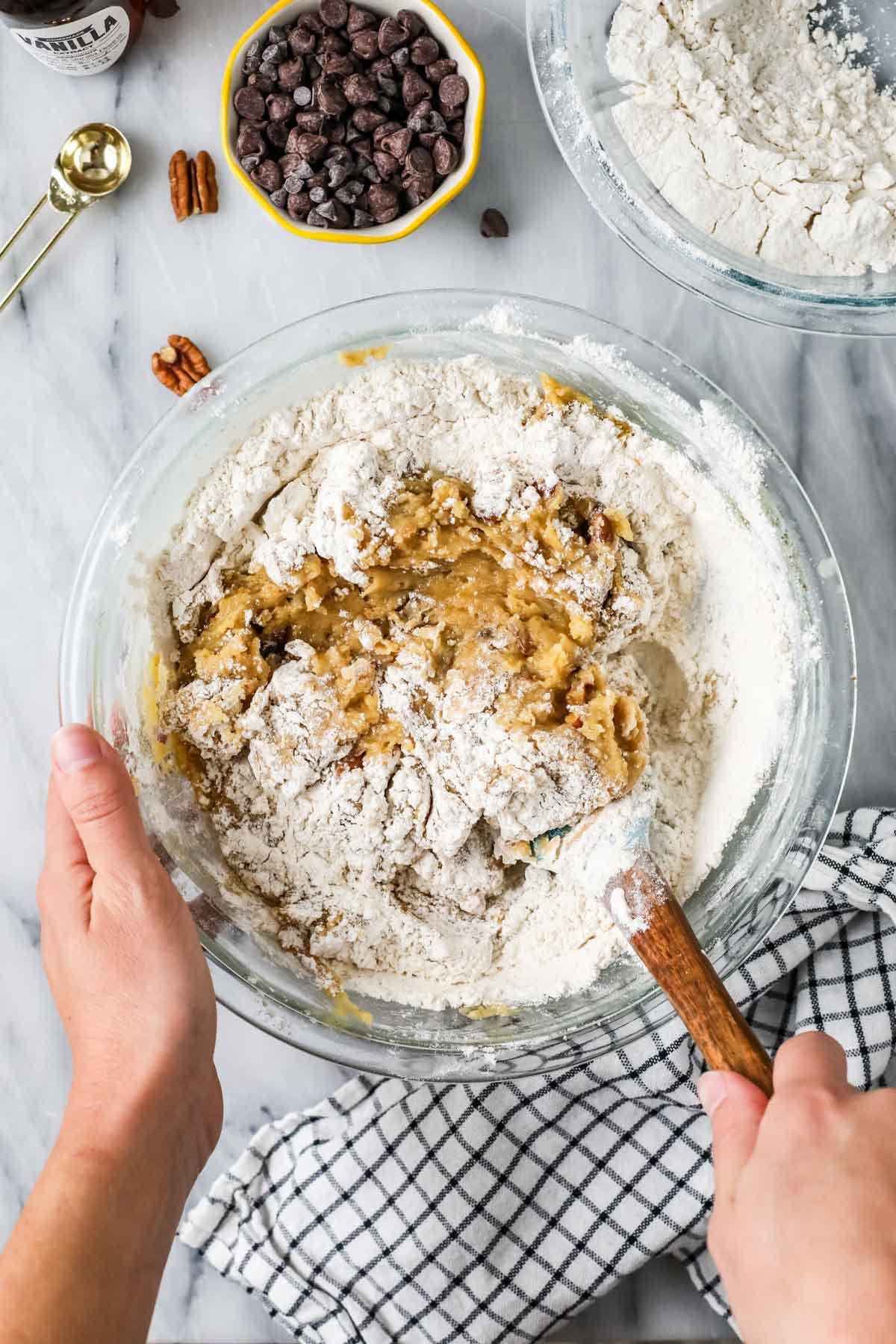 Overhead view of dry ingredients being folded into cookie dough.