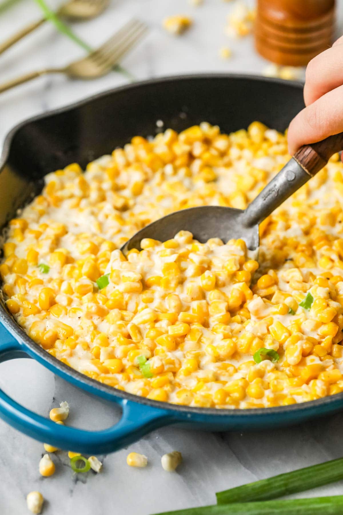 Spoon scooping creamed corn out of a skillet.