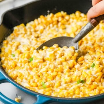 Spoon scooping creamed corn out of a skillet.