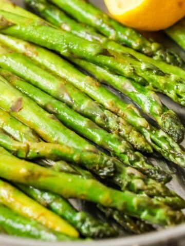 Asparagus spears in a saucepan after being sautéed with lemon and butter.