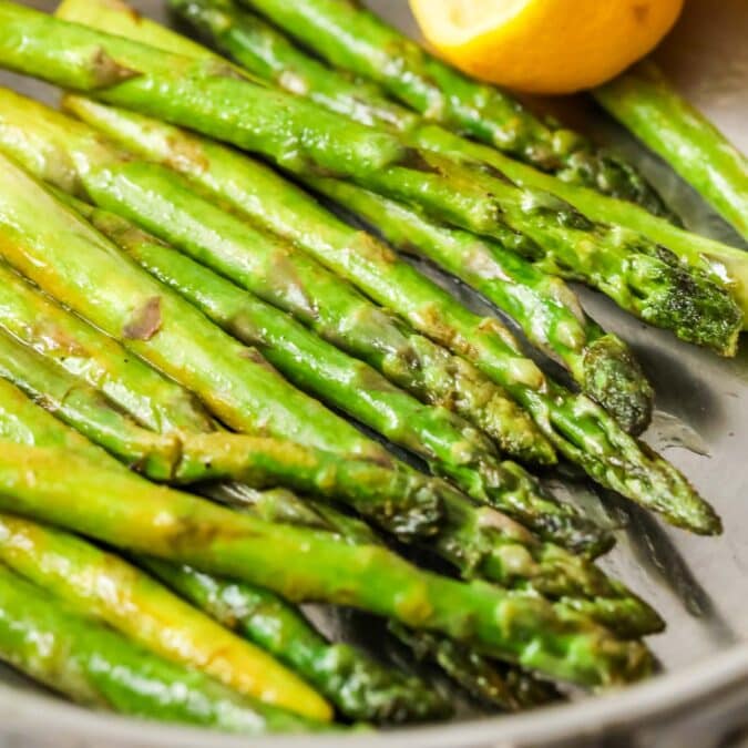 Asparagus spears in a saucepan after being saut&eacute;ed with lemon and butter.
